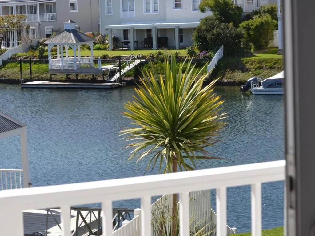 Waterfront lagoon view with boats, gazebo, and manicured gardens from deck