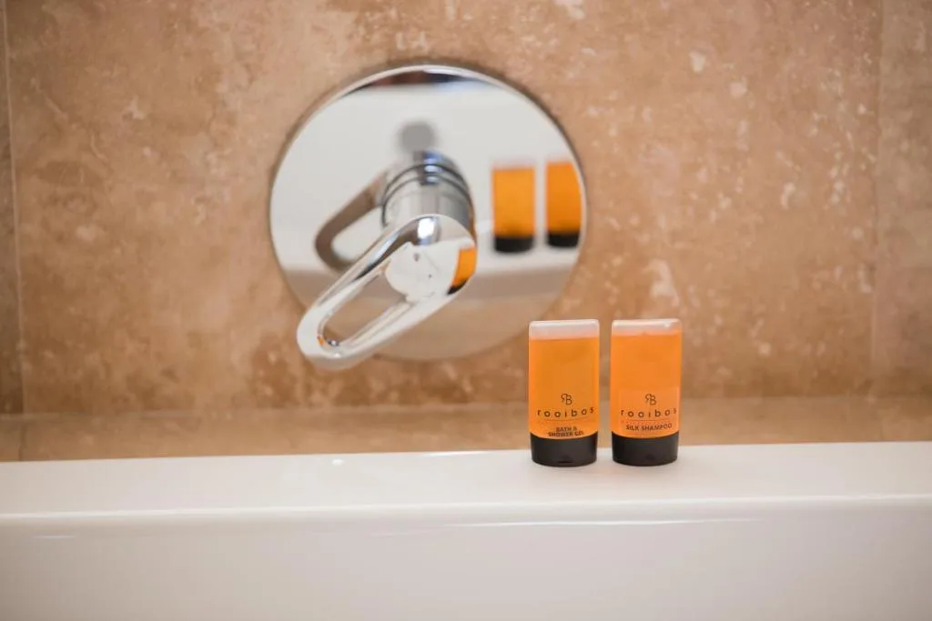 Modern shower fixture with luxury toiletries on vanity edge