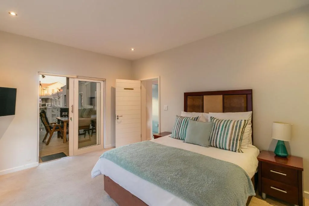 Spacious bedroom with queen bed, striped pillows, and glass doors opening to lounge area