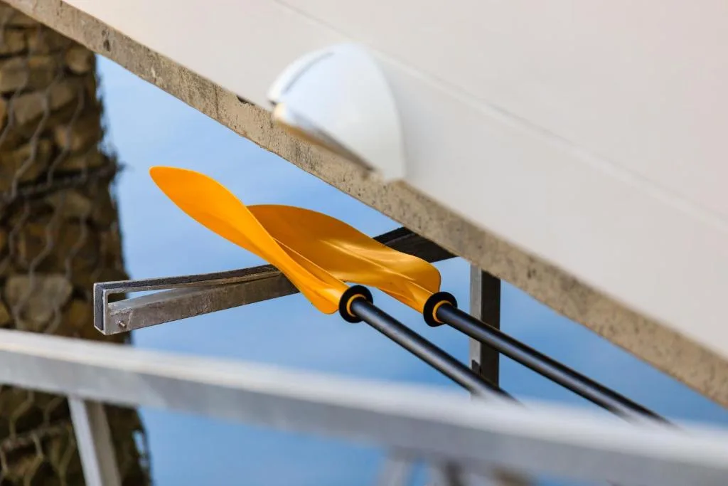 Yellow kayak paddles mounted on property railing with clear blue sky