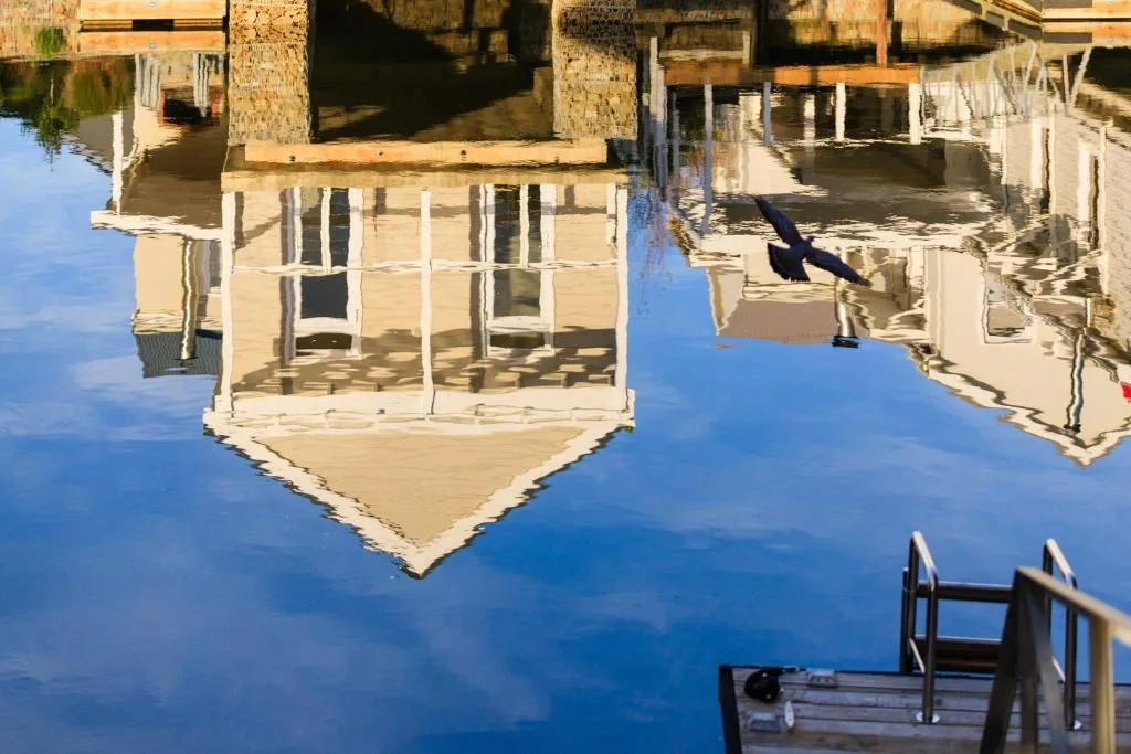 Reflection of waterfront house in calm blue water below