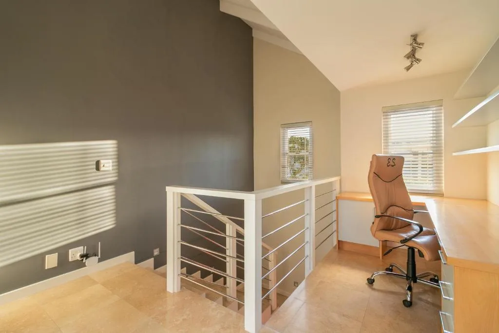 Modern home office with desk, chair, and staircase railing
