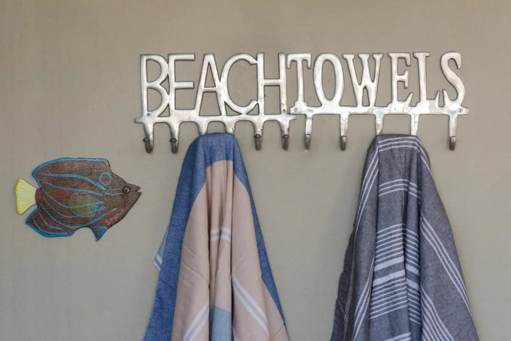 Beach towels rack with decorative fish wall art and coastal signage