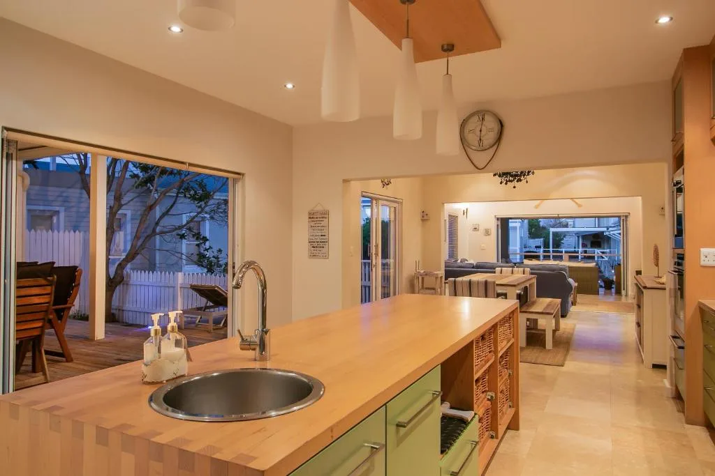 Modern kitchen with wooden counters, green cabinetry, and island seating area