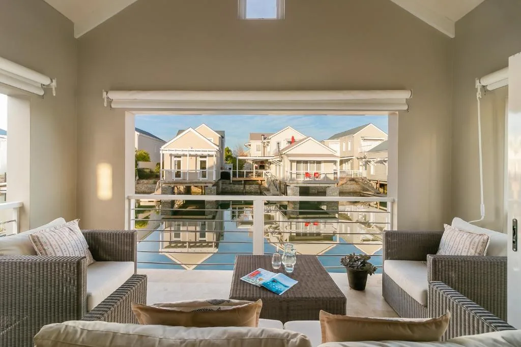 Spacious lounge with rattan seating overlooking waterfront homes and lagoon