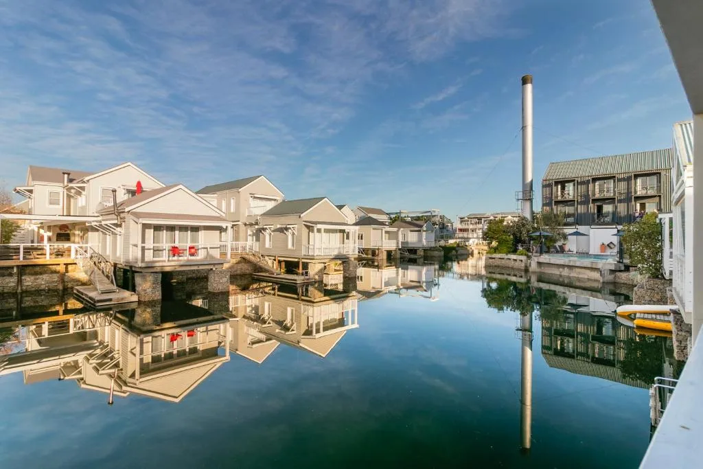 Waterfront village with cream cottages reflected in calm lagoon water