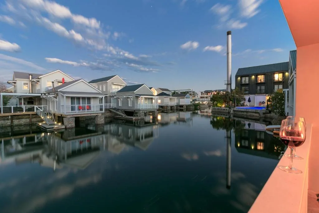 Waterfront view of Thesen Island's charming cottage homes reflected in calm lagoon waters
