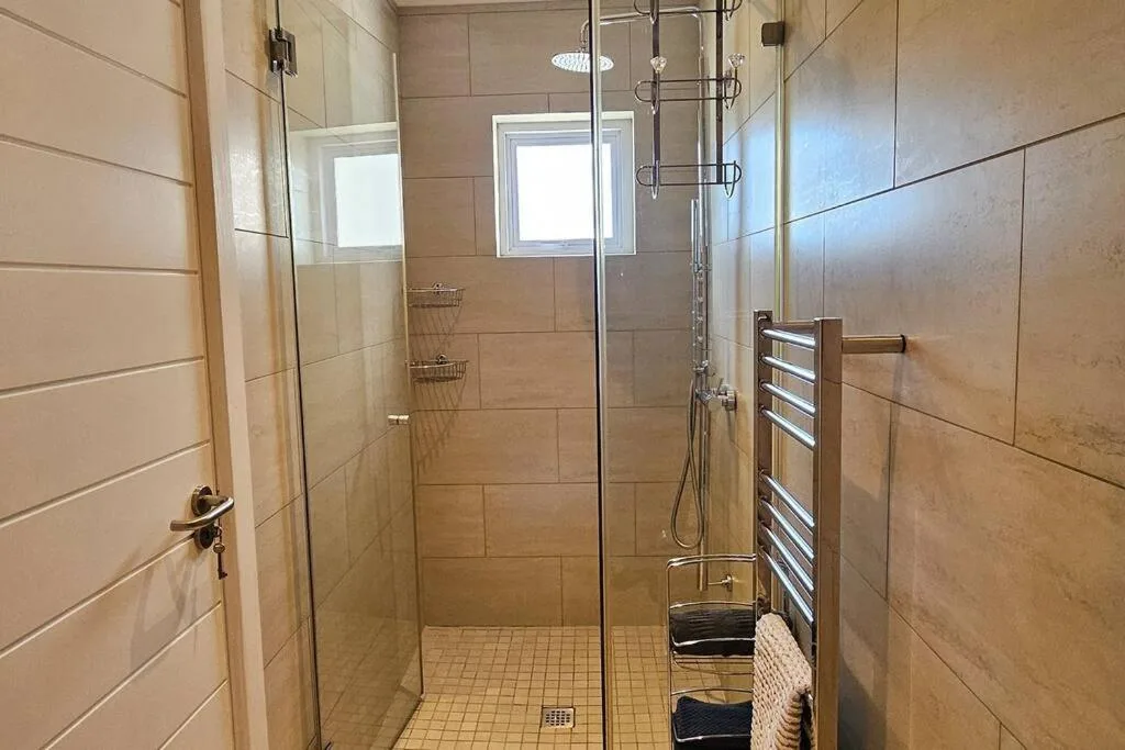 Modern walk-in shower with glass enclosure and heated towel rail