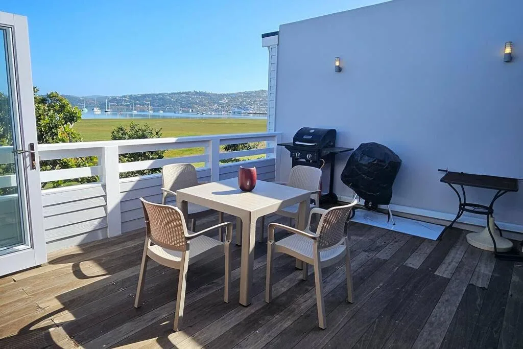 Spacious waterfront deck with dining table, braai grill, and stunning lagoon views