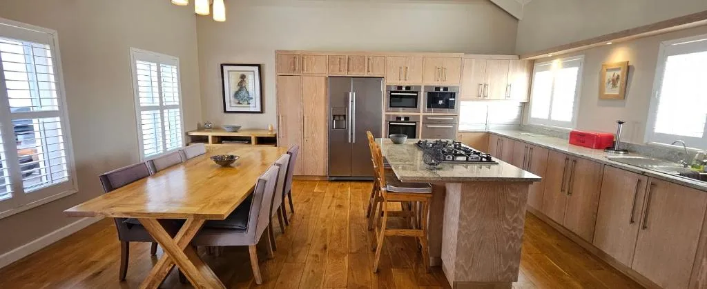 Modern open-plan kitchen and dining area with wooden cabinetry and stainless steel appliances