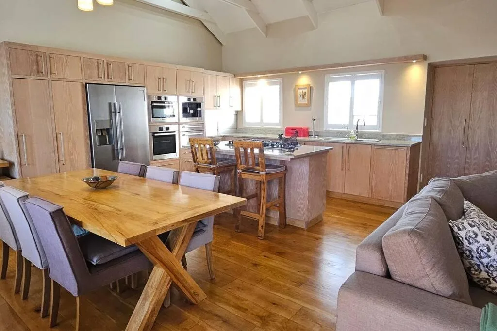Modern open-plan kitchen with wooden cabinetry and stainless steel appliances