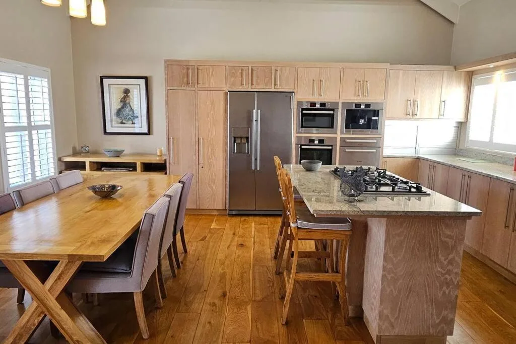 Open-plan kitchen with wooden cabinetry, island countertop, and dining table seating