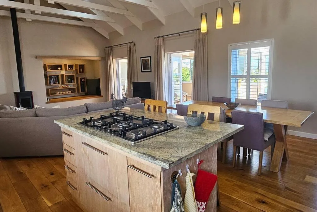 Open-plan lounge and dining area with gas cooktop island, sofa, and entertainment unit