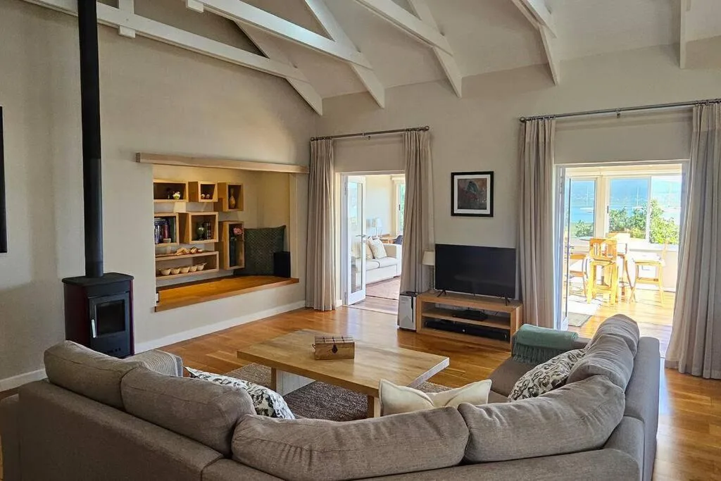 Spacious modern lounge with gray sofa, fireplace, and ocean views through glass doors