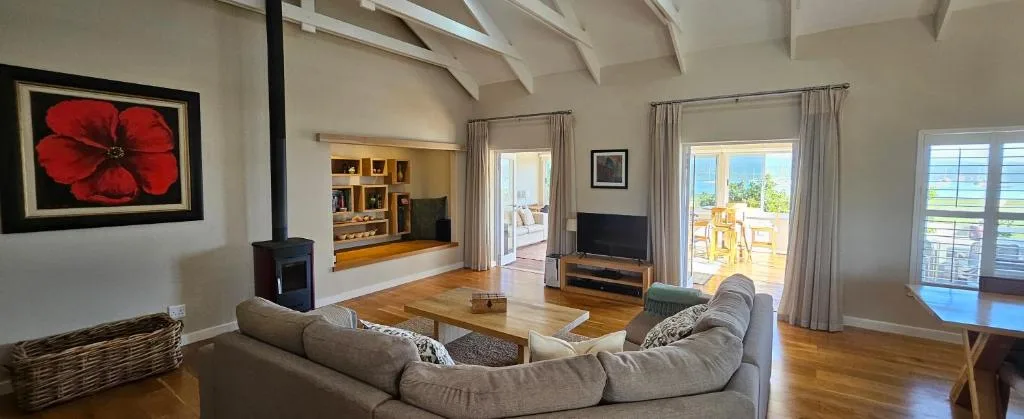 Spacious open-plan lounge with curved sofa, fireplace, and ocean view doors