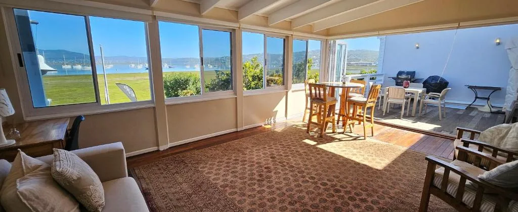Spacious lounge with coastal lagoon views through expansive windows and glass doors