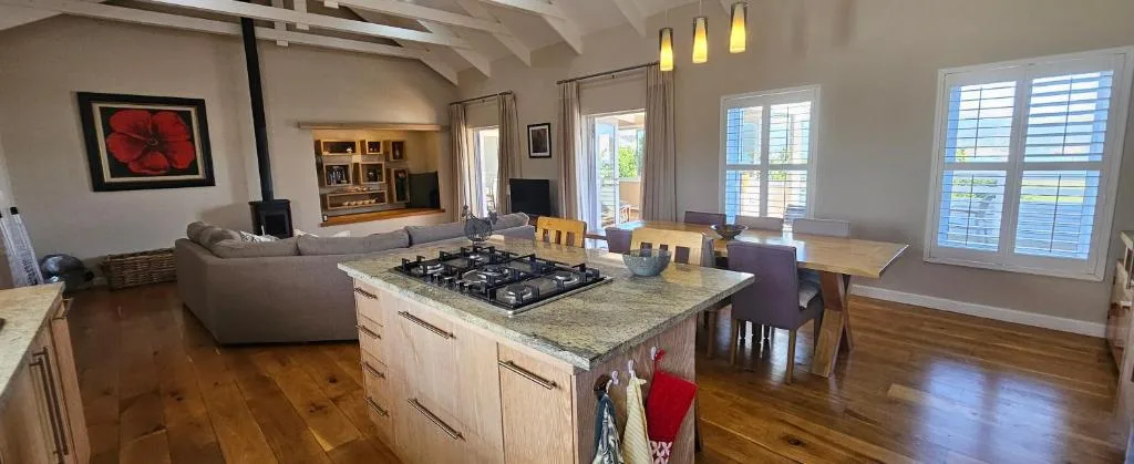 Open-plan living area with sofa, gas cooktop island, and dining table