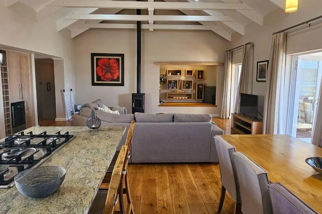 Open-plan lounge with gray sofa, wood flooring, vaulted ceilings, fireplace