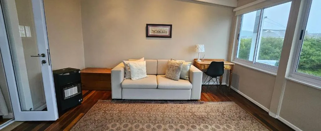 Bright living room with cream sofa, fireplace, and large windows overlooking garden