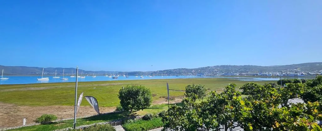 Scenic lagoon view with moored boats and coastal town hills beyond