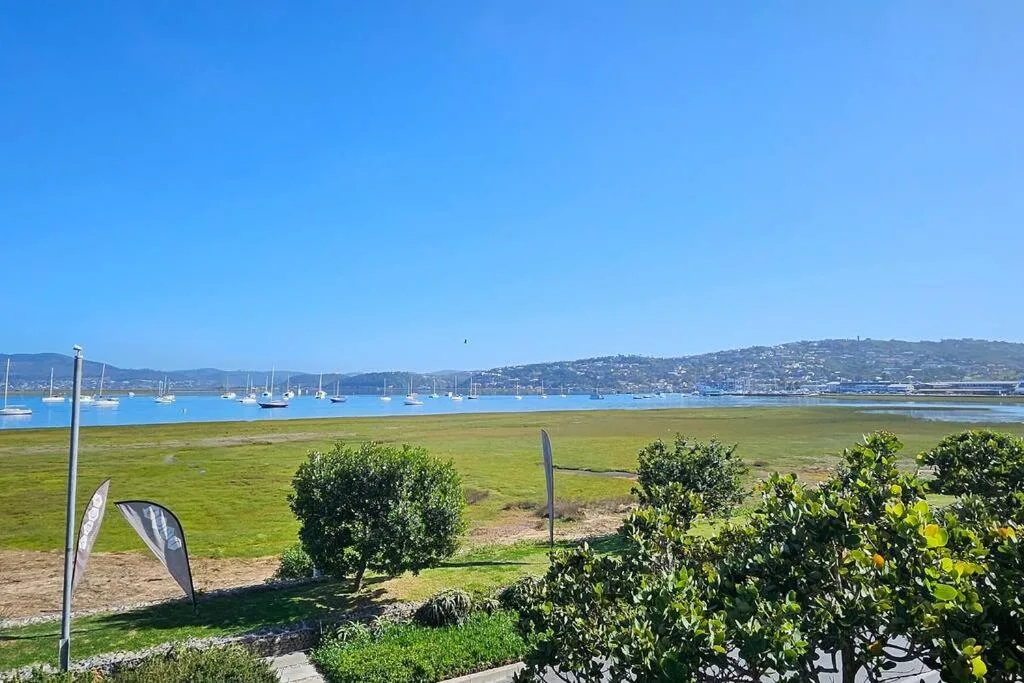 Scenic lagoon view with moored sailboats and green hillside beyond
