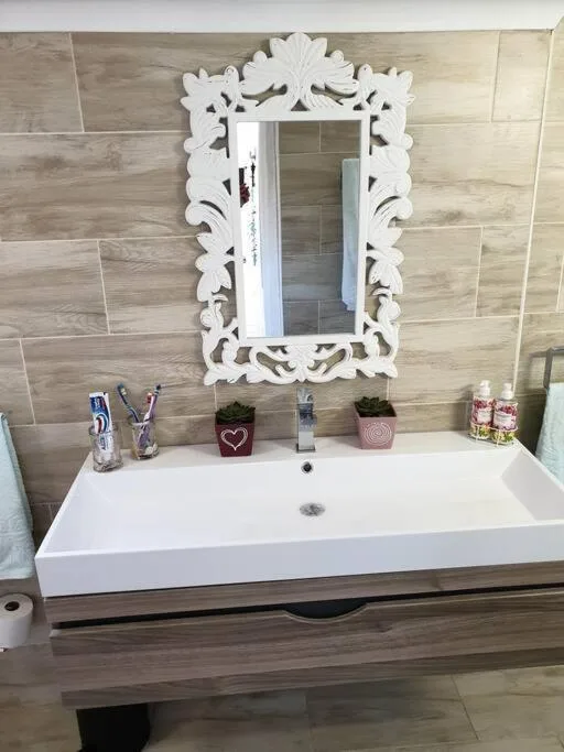 Modern bathroom vanity with white ornate mirror and wooden tile accents