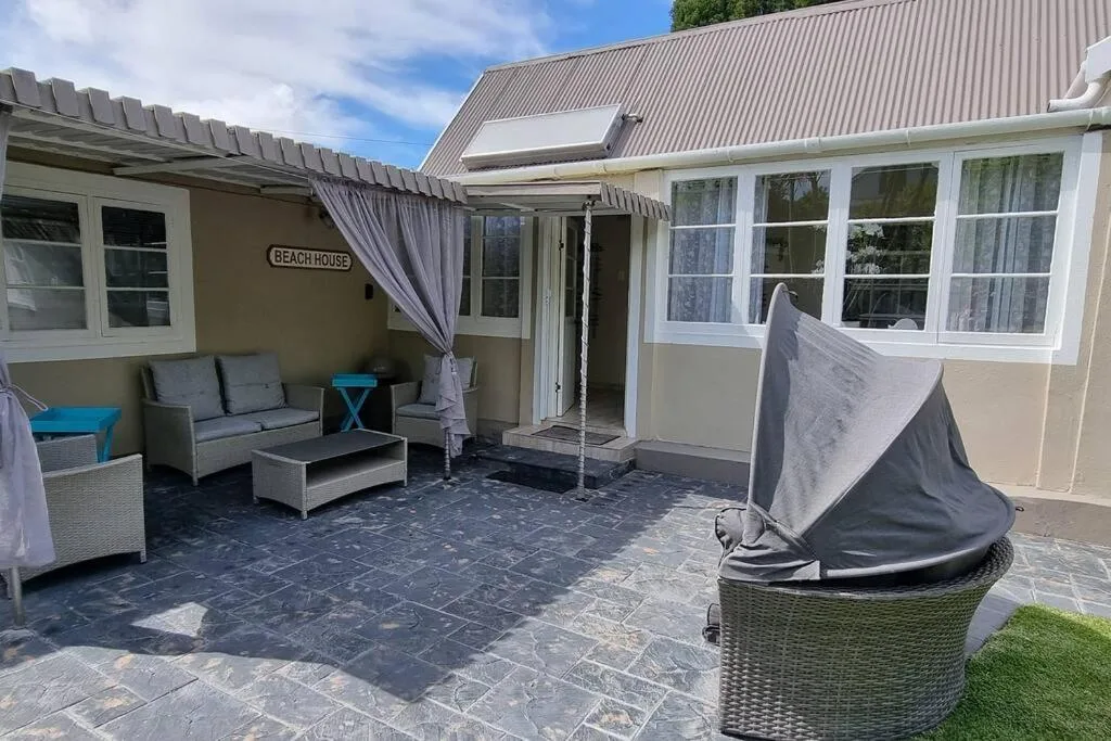 Covered patio with outdoor seating, fire pit, and beach house entrance