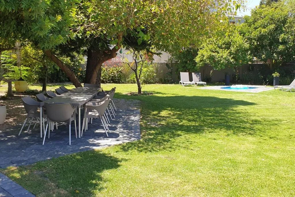 Shaded outdoor dining area with table and chairs under mature trees