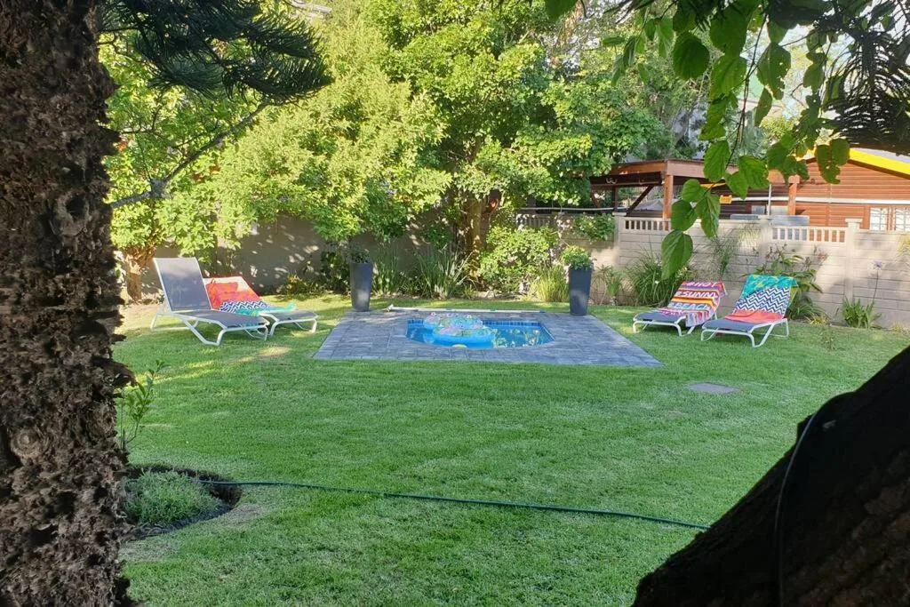 Shaded garden with loungers, pool, and mature trees for relaxation