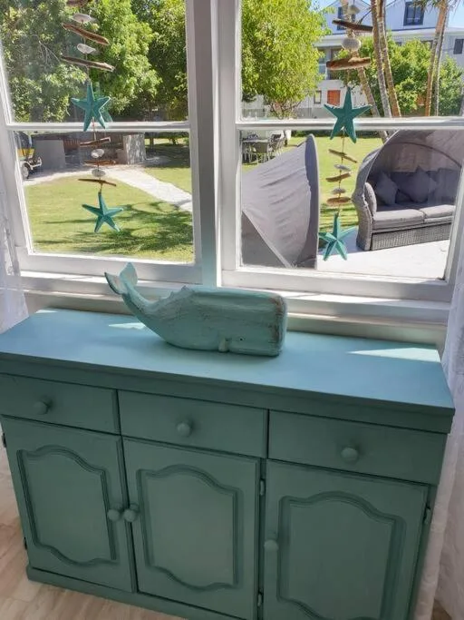 Green vintage dresser with whale decoration beside window overlooking garden