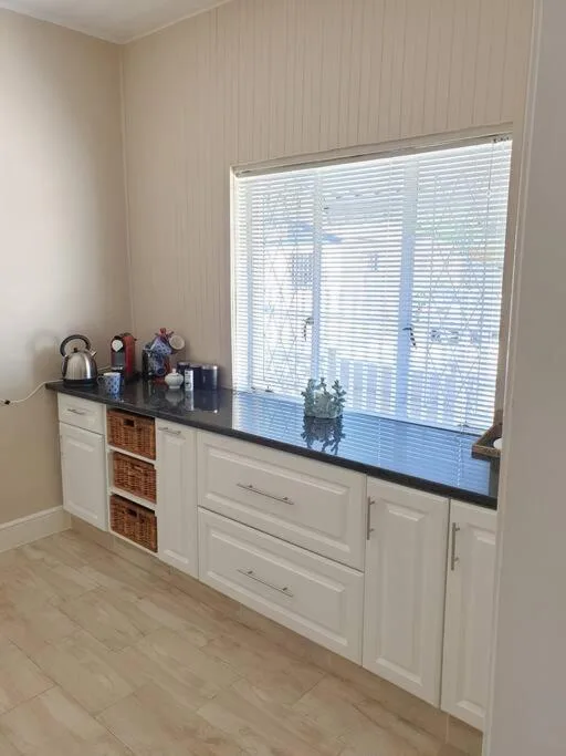 White cabinetry with black countertop and wicker storage baskets near window