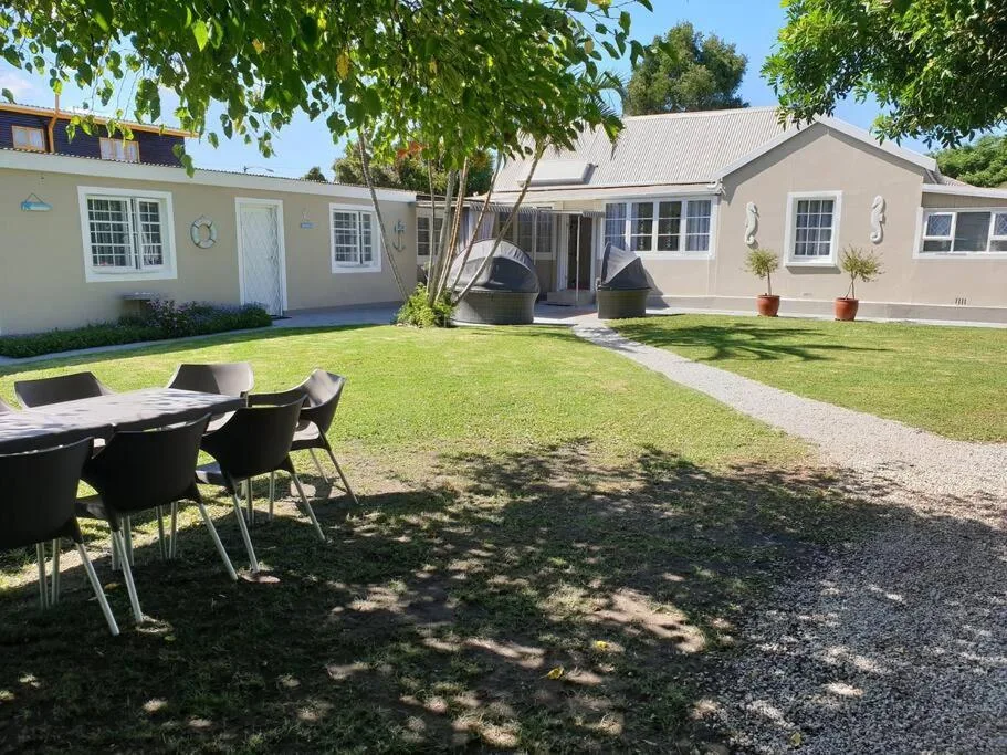 Modern cottage exterior with green lawn, outdoor seating, and landscaped gardens