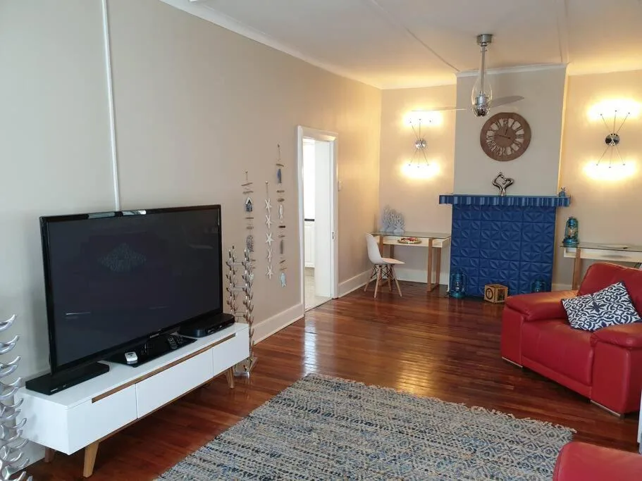 Modern lounge with red sofa, flat-screen TV, wooden floors, warm lighting