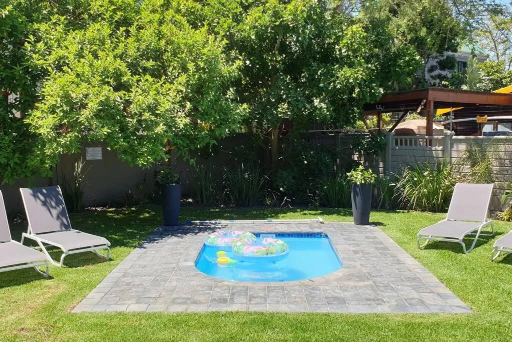 Blue kiddie pool with floats in manicured garden surrounded by loungers