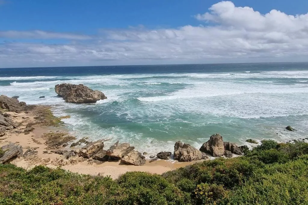 Scenic coastal view with rocky beach, turquoise waves, and blue sky