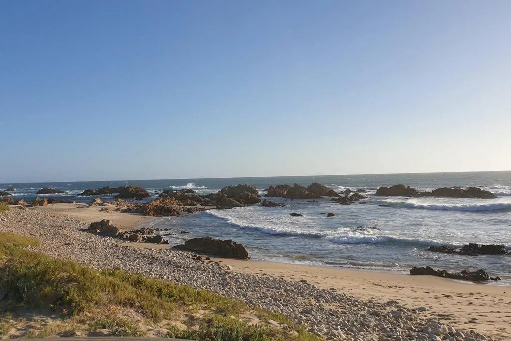 Scenic rocky beach with waves and golden sand, Garden Route coastal vista