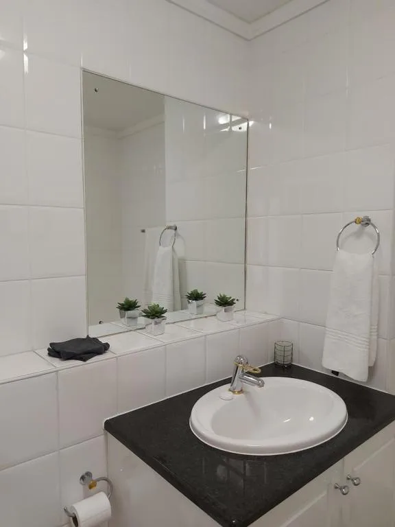 Modern bathroom with round white sink, black countertop, large mirror, white subway tiles