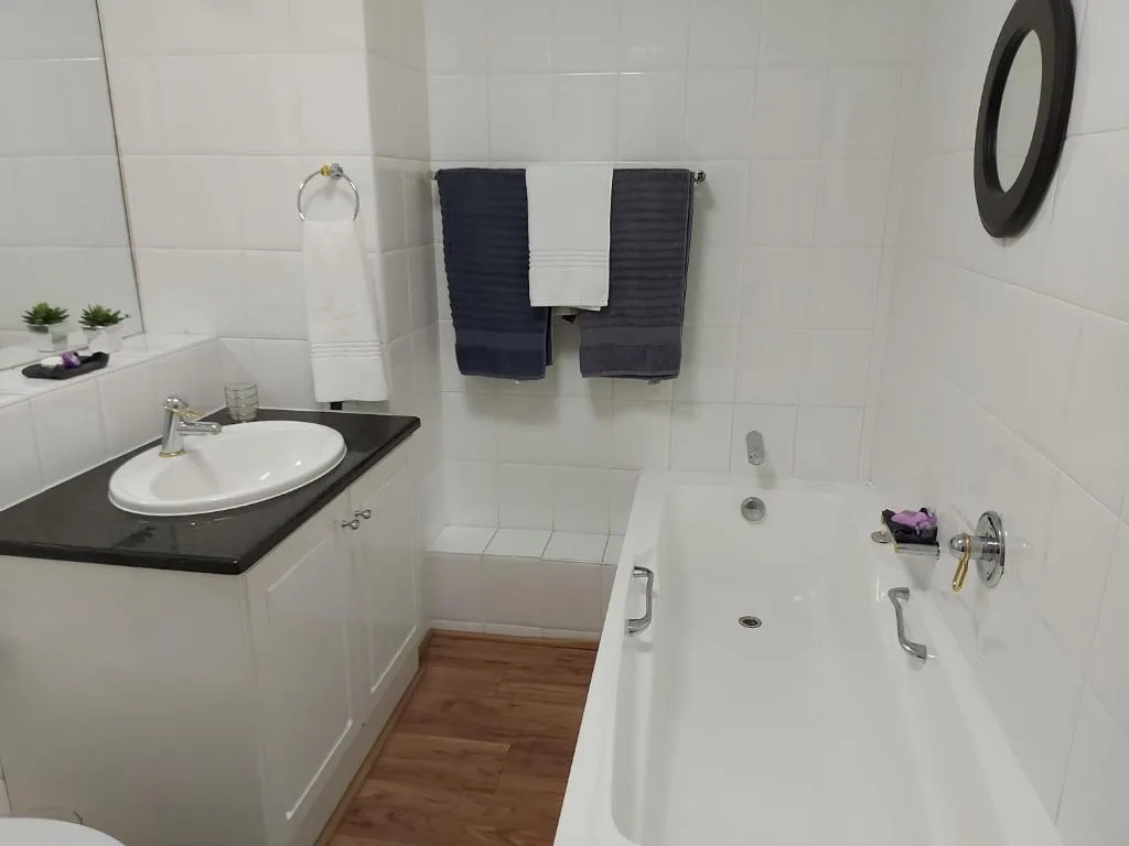 Modern bathroom with white tiles, black vanity, and soaking tub
