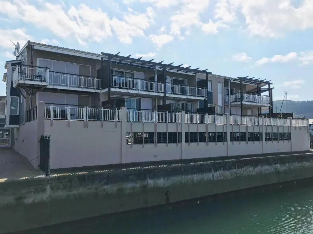 Modern waterfront apartment building with multiple decks overlooking Knysna lagoon