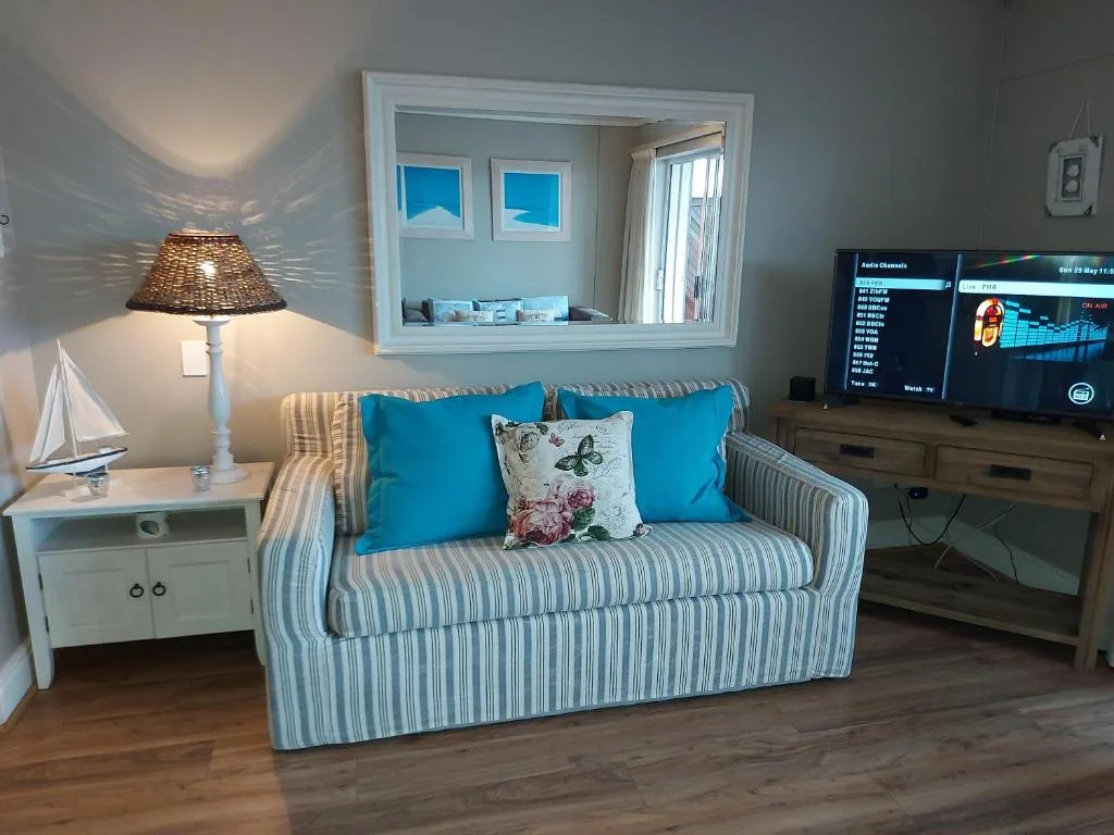 Bright coastal lounge with striped sofa, blue pillows, and wall-mounted mirror