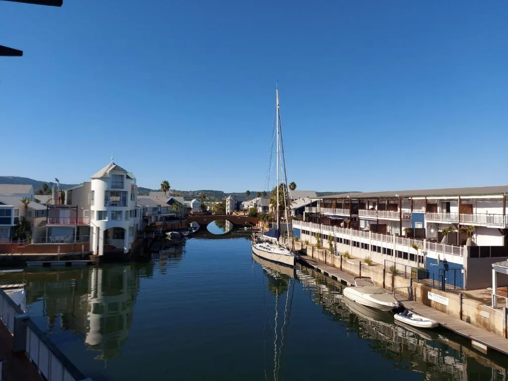 Scenic waterfront view of Knysna Quays with sailboat and lagoon