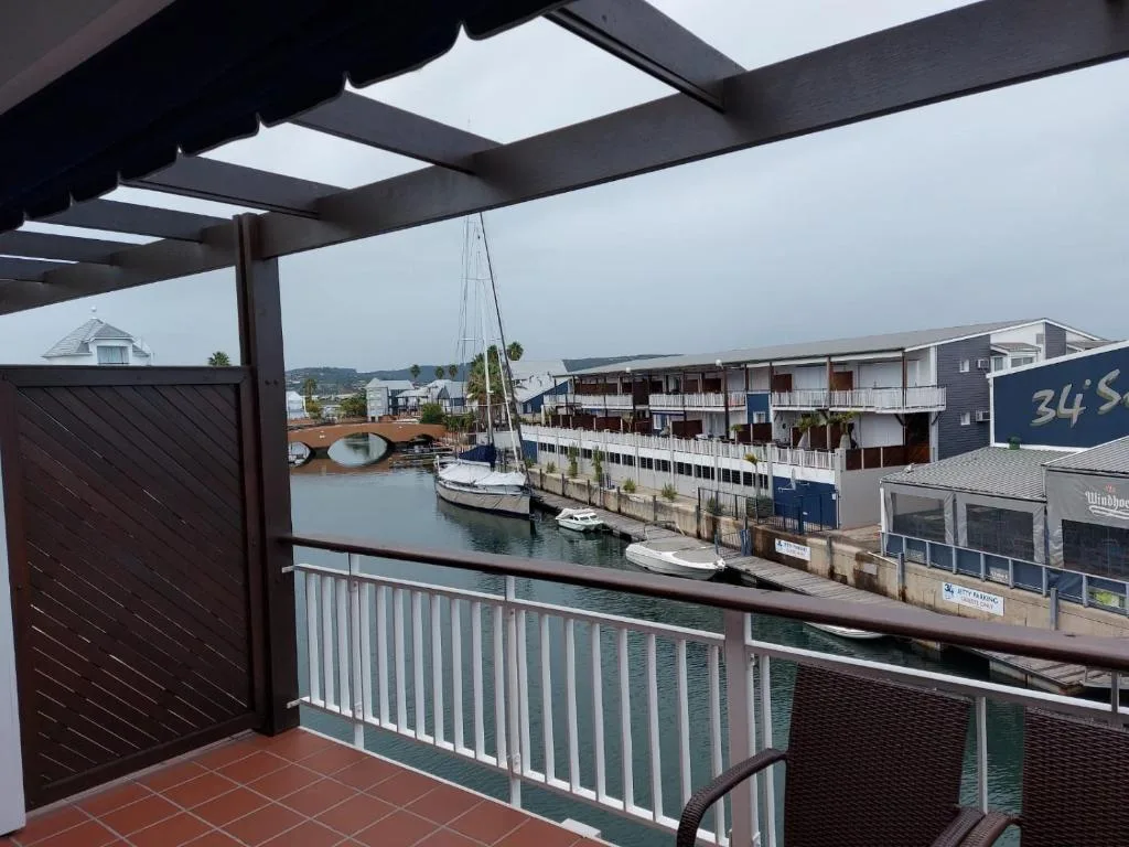 Scenic waterfront view of Knysna Heads with moored sailboats and quayside buildings