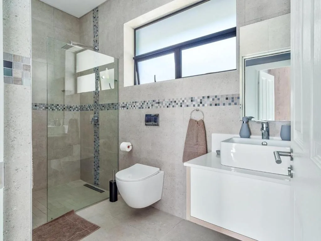 Modern bathroom with walk-in shower, wall-mounted toilet, and double vanity