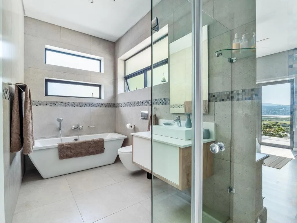 Modern bathroom with freestanding tub, glass shower enclosure, and scenic view