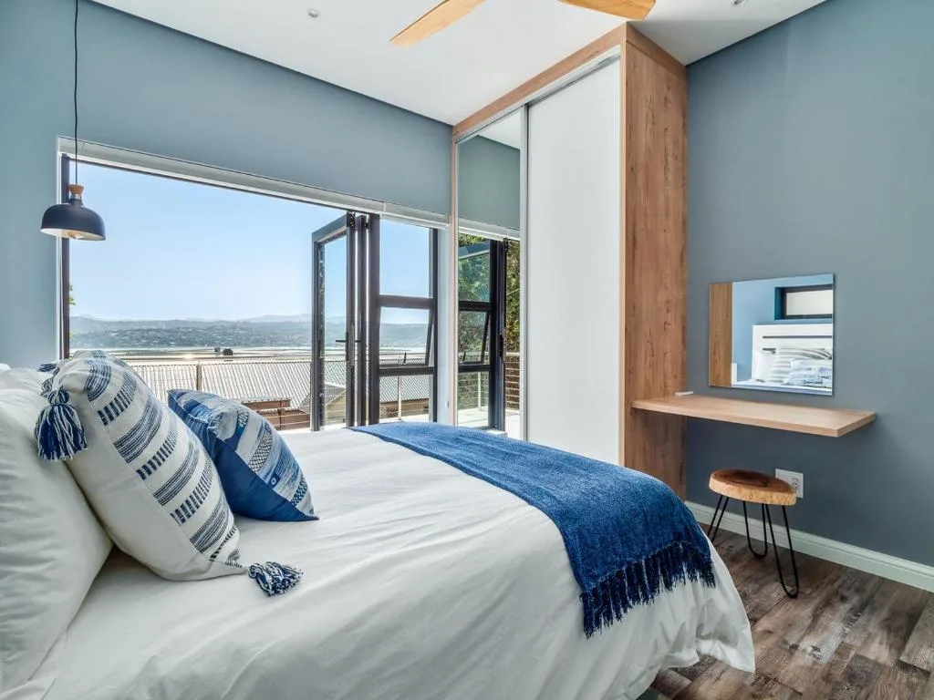 Modern bedroom with ocean view through glass doors and balcony access