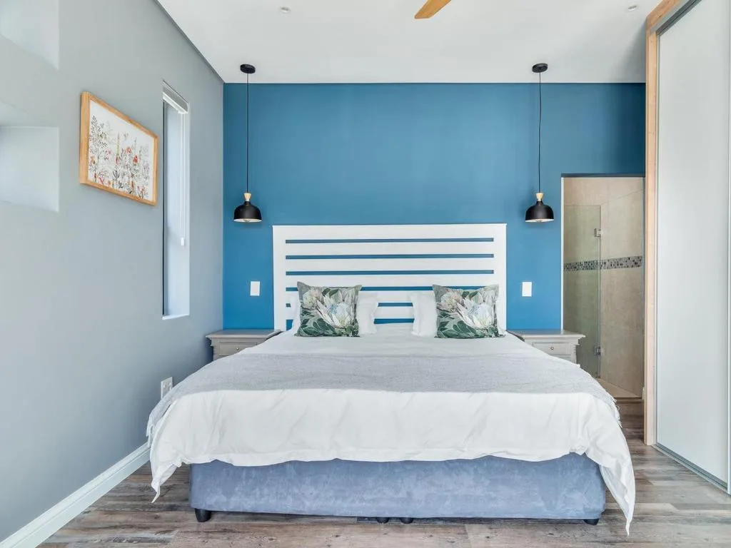 Bright bedroom with bold blue accent wall and white striped headboard