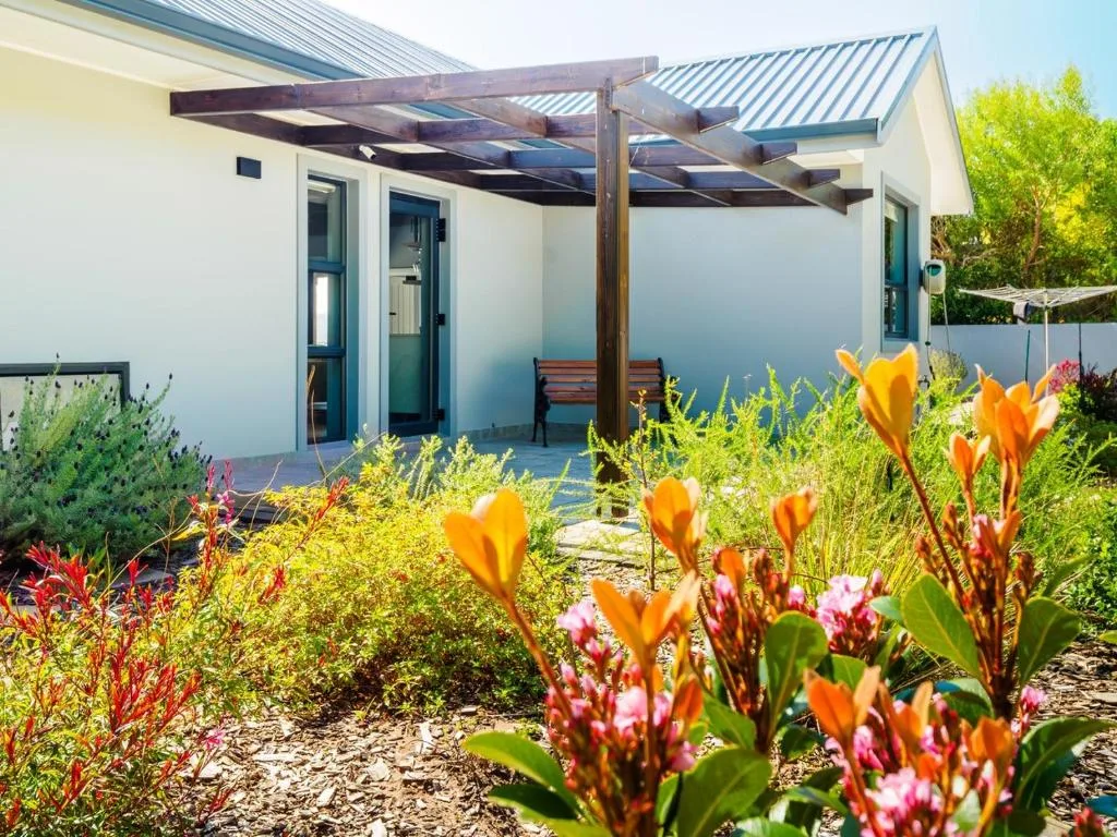 Modern pergola-covered patio with colorful flowering garden and wooden bench