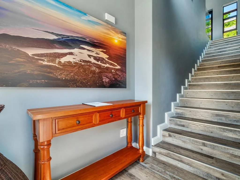 Wooden console table and scenic landscape artwork in modern entryway
