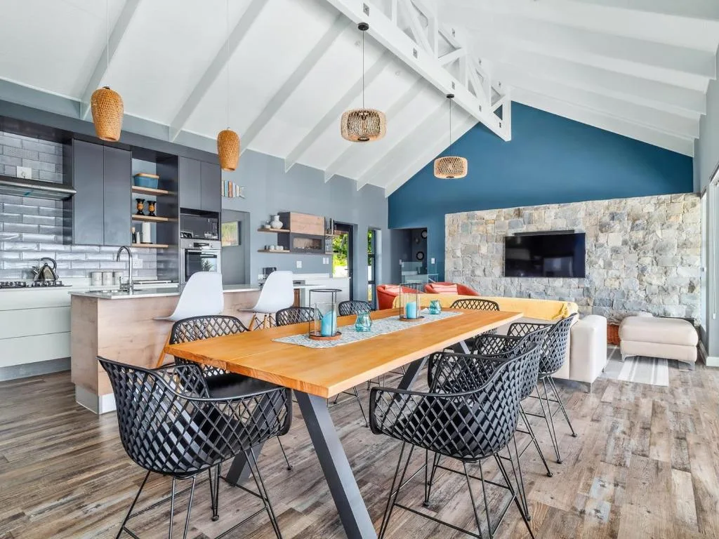Open-plan dining area with wooden table and black chairs, stone fireplace visible