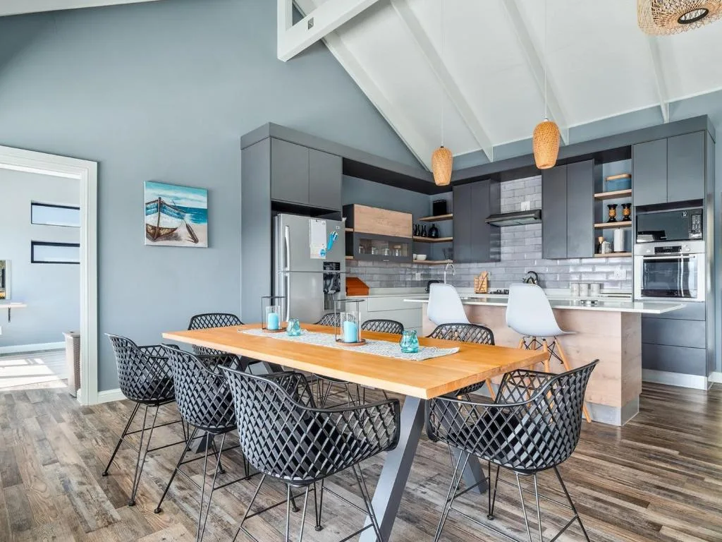 Modern dining area with wooden table and patterned black chairs overlooking kitchen